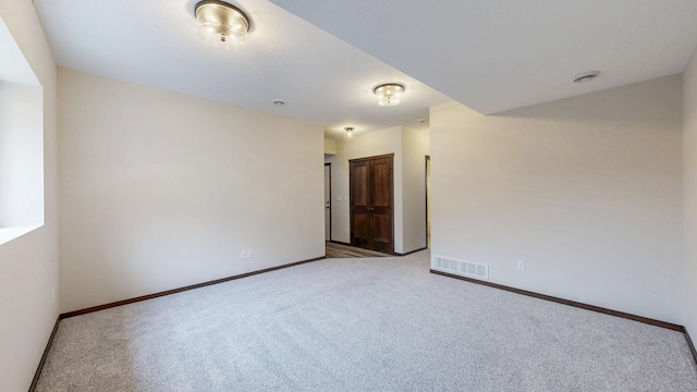 empty room with baseboards, visible vents, and light colored carpet