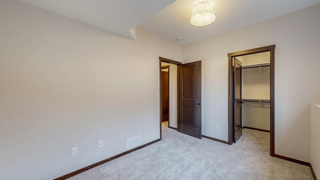 unfurnished bedroom with baseboards, visible vents, light colored carpet, a spacious closet, and a closet