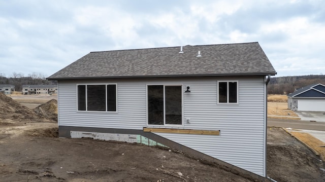 rear view of property with roof with shingles