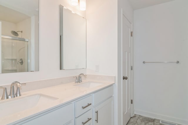 full bath featuring a shower with shower door, a sink, baseboards, and double vanity