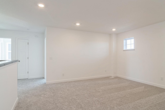 spare room featuring recessed lighting, light carpet, and baseboards