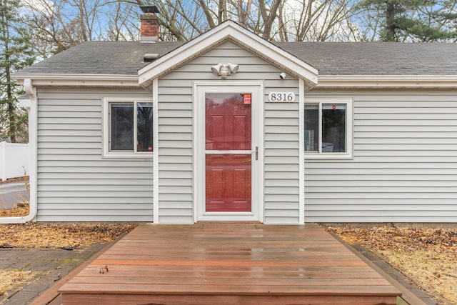 property entrance with a chimney and a shingled roof