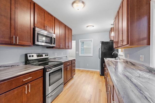 kitchen featuring light wood-style flooring, baseboards, and appliances with stainless steel finishes