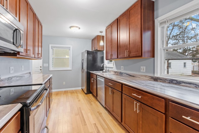 kitchen featuring a sink, stainless steel appliances, light wood-type flooring, and plenty of natural light