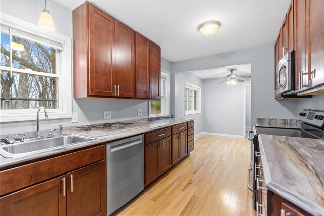 kitchen featuring ceiling fan, pendant lighting, appliances with stainless steel finishes, light wood-style floors, and a sink