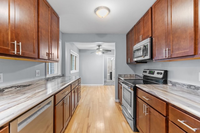 kitchen with appliances with stainless steel finishes, brown cabinetry, light wood finished floors, baseboards, and ceiling fan