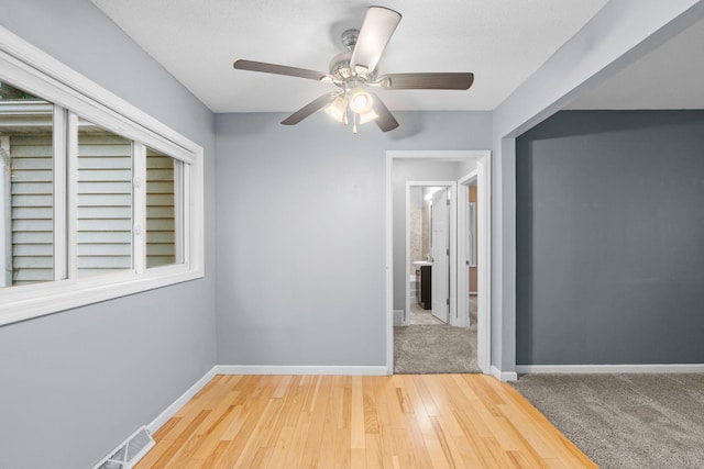 unfurnished room featuring visible vents, a ceiling fan, baseboards, and wood finished floors