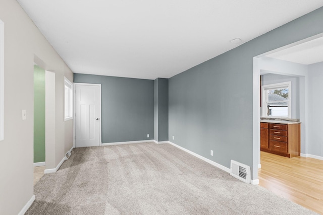 spare room featuring light colored carpet, baseboards, and visible vents