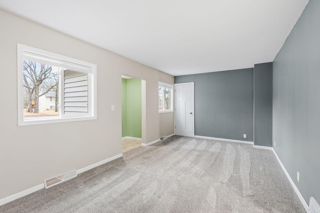 carpeted spare room with visible vents and baseboards