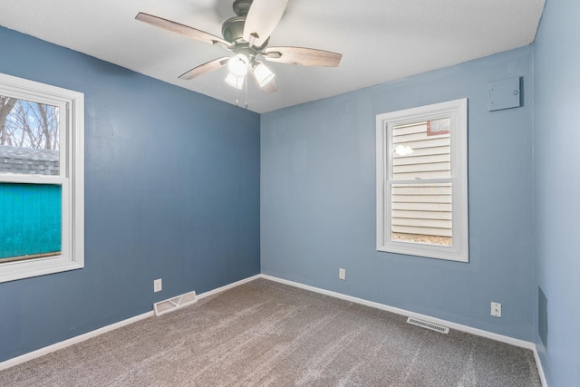 carpeted empty room with visible vents, baseboards, and a ceiling fan