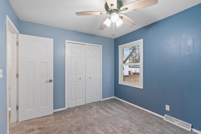 unfurnished bedroom with baseboards, visible vents, ceiling fan, a closet, and carpet flooring