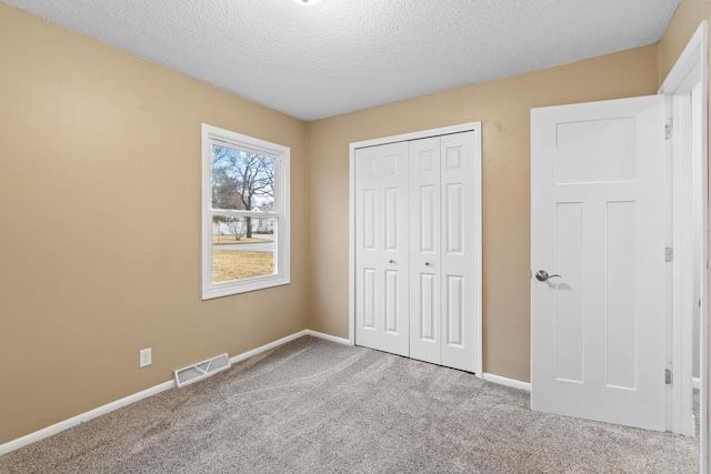 unfurnished bedroom with carpet flooring, baseboards, visible vents, and a closet