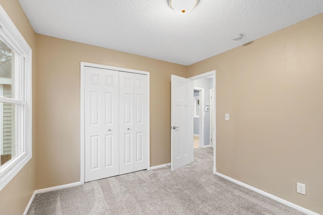 unfurnished bedroom featuring a closet, a textured ceiling, baseboards, and carpet floors