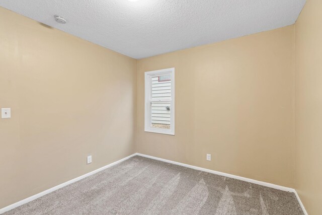 carpeted spare room featuring a textured ceiling and baseboards