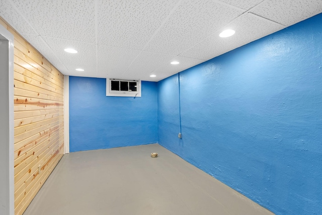 empty room with a drop ceiling, recessed lighting, finished concrete flooring, and a textured wall