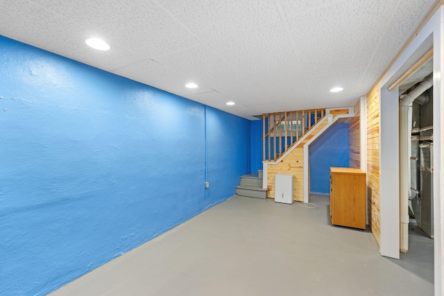 finished basement with stairway, recessed lighting, and a textured wall