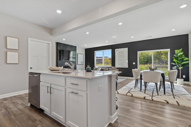 kitchen with light countertops, a healthy amount of sunlight, white cabinetry, a sink, and wood finished floors