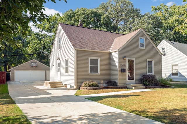 view of front of house with a garage, a shingled roof, a front lawn, and an outbuilding