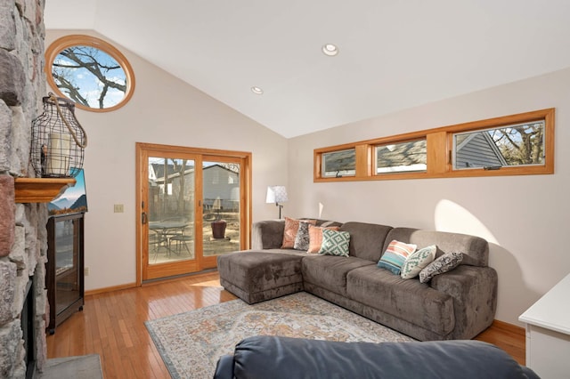 living room featuring recessed lighting, light wood-style floors, a glass covered fireplace, high vaulted ceiling, and baseboards