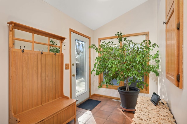 interior space featuring a healthy amount of sunlight, tile patterned flooring, baseboards, and vaulted ceiling