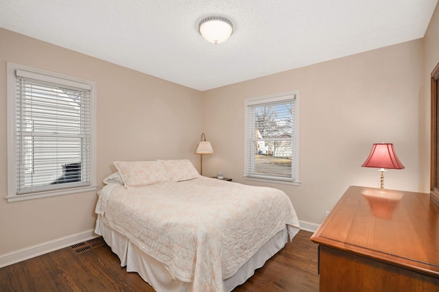 bedroom with dark wood-style flooring, visible vents, and baseboards