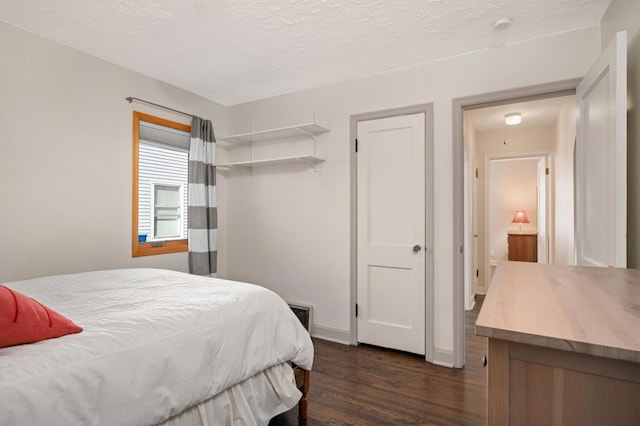 bedroom with a textured ceiling, baseboards, and dark wood-style flooring