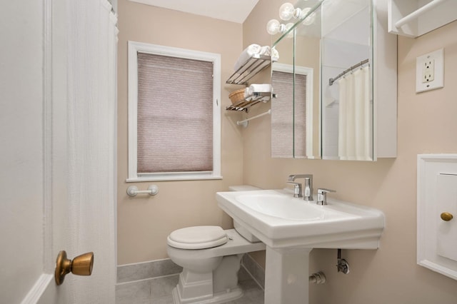 bathroom with baseboards, toilet, and tile patterned floors