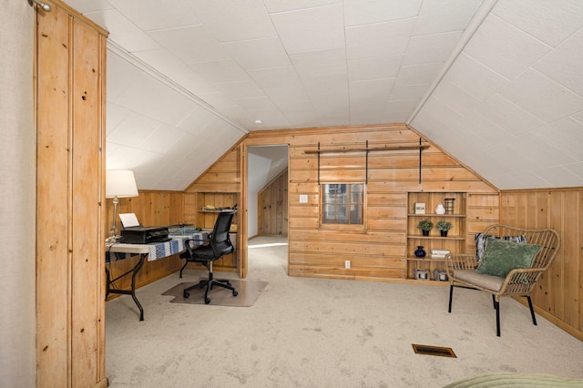 carpeted office featuring vaulted ceiling, visible vents, and wooden walls