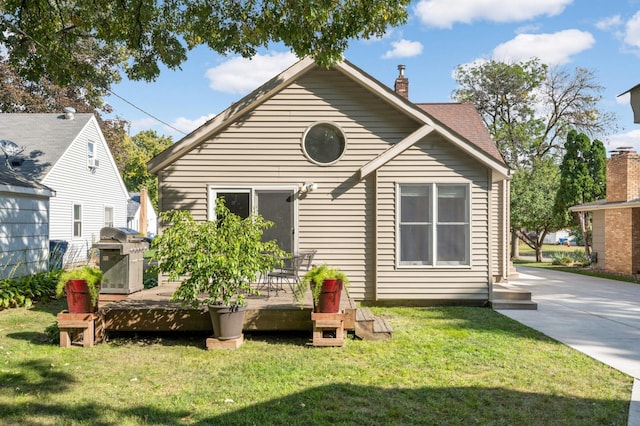 rear view of property featuring a yard, a chimney, and a wooden deck