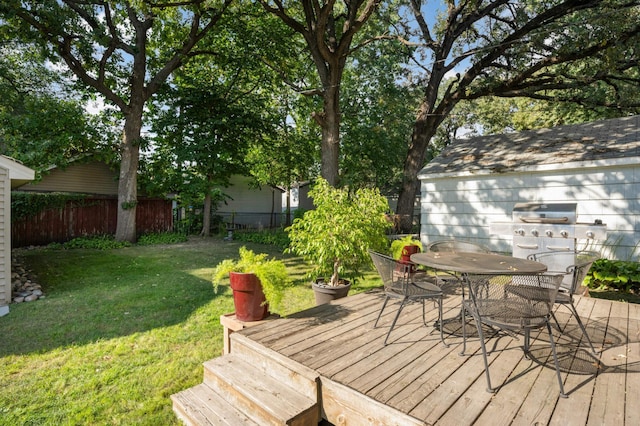 wooden terrace with outdoor dining space, fence, grilling area, and a yard