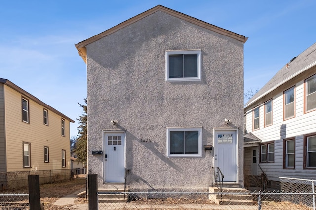 back of property with entry steps, fence private yard, and stucco siding