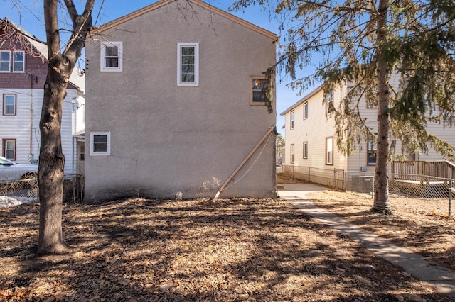 back of property with central air condition unit, fence, and stucco siding