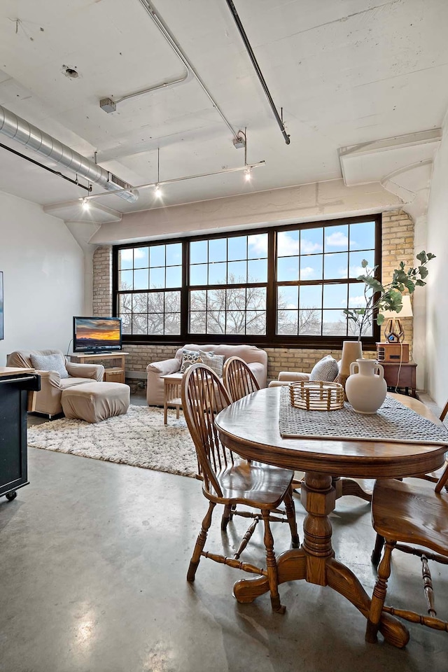 dining area with plenty of natural light, concrete flooring, and brick wall