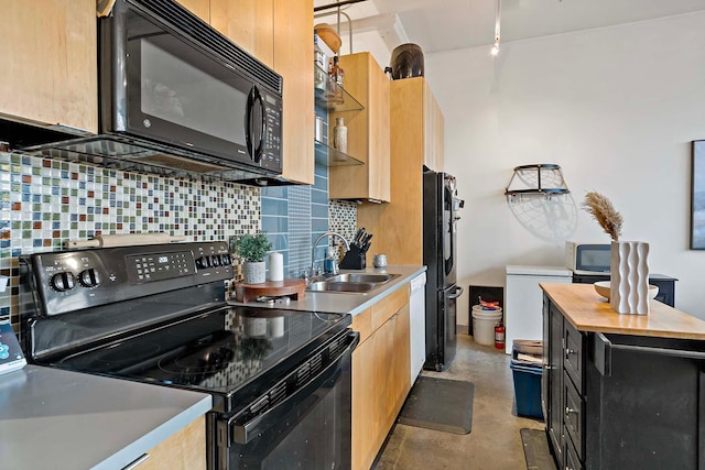 kitchen with backsplash, butcher block countertops, concrete flooring, black appliances, and a sink