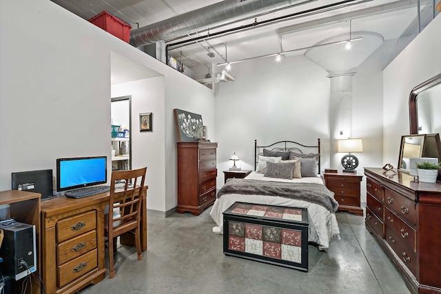 bedroom with finished concrete flooring and track lighting