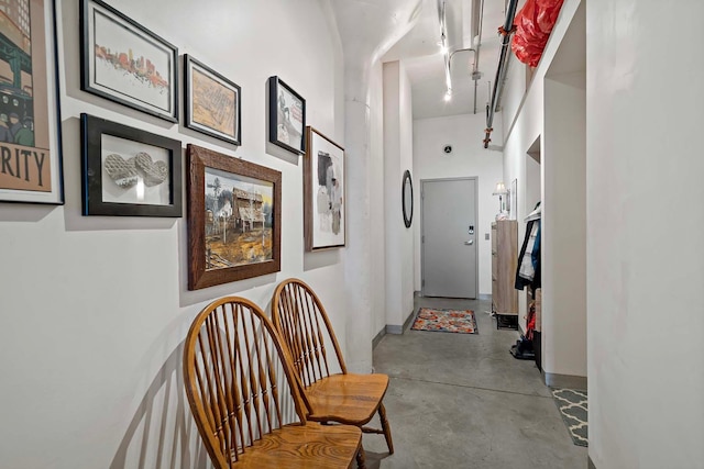 hall with baseboards, a high ceiling, and concrete floors