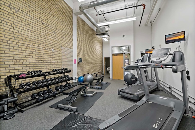 workout area with brick wall and a towering ceiling