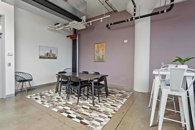 dining room with rail lighting, baseboards, and finished concrete floors