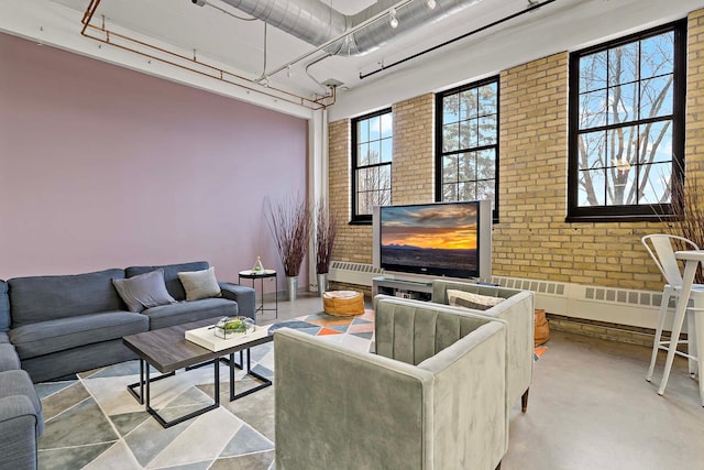 living area with rail lighting, concrete floors, brick wall, and a towering ceiling