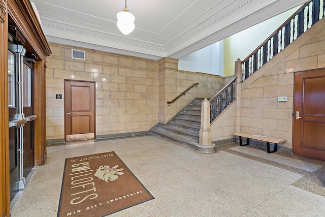 interior space with stairway, concrete block wall, visible vents, and ornamental molding