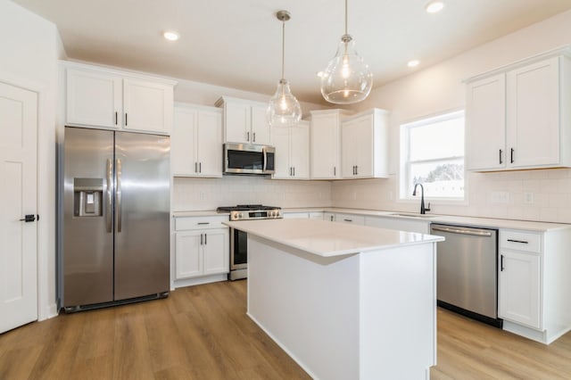 kitchen featuring decorative backsplash, appliances with stainless steel finishes, white cabinetry, and light wood-style floors