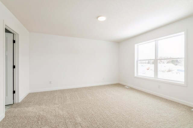 empty room with light colored carpet and baseboards