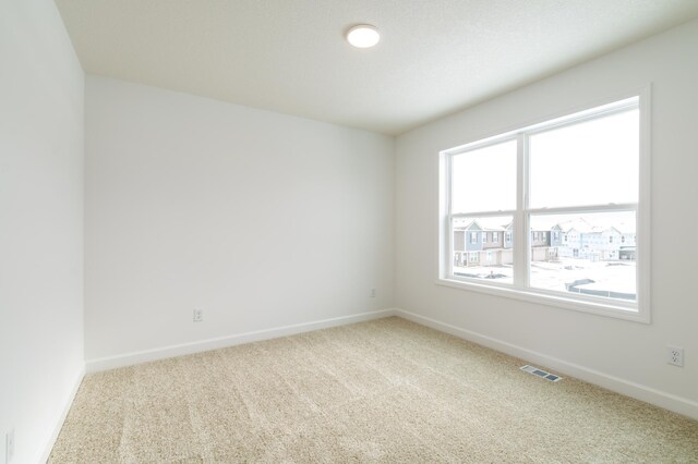 carpeted spare room with visible vents and baseboards