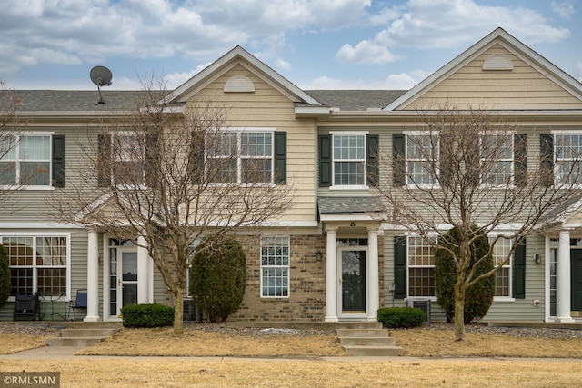 townhome / multi-family property with brick siding and central AC unit