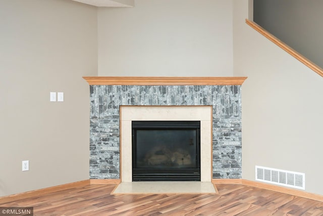 room details with a fireplace with flush hearth, visible vents, and wood finished floors