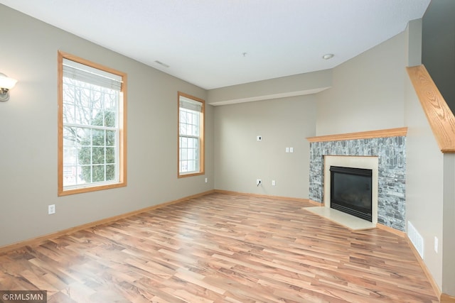 unfurnished living room featuring a fireplace with flush hearth, visible vents, light wood-style flooring, and baseboards