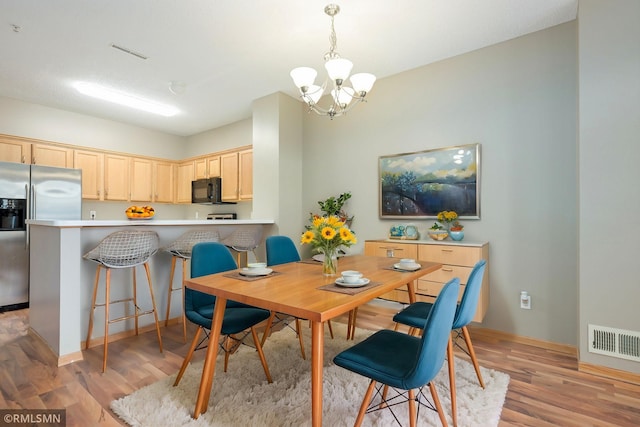 dining room with light wood-style floors, visible vents, and a notable chandelier