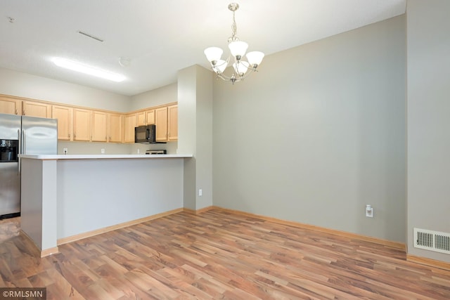 kitchen with black microwave, visible vents, light wood-style flooring, and stainless steel fridge with ice dispenser