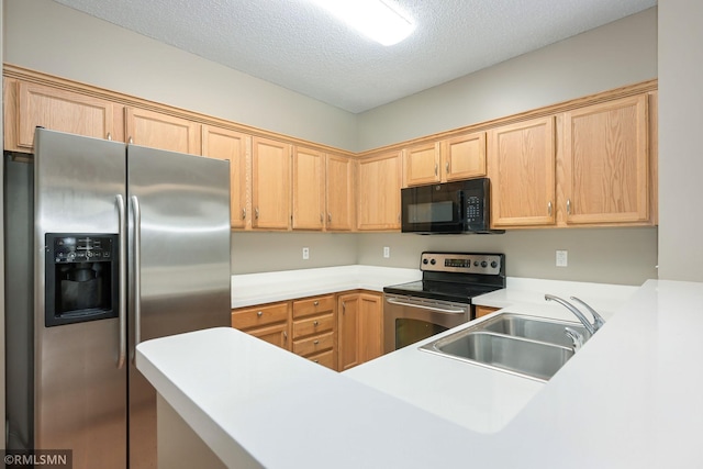 kitchen featuring stainless steel appliances, light countertops, light brown cabinetry, a sink, and a textured ceiling