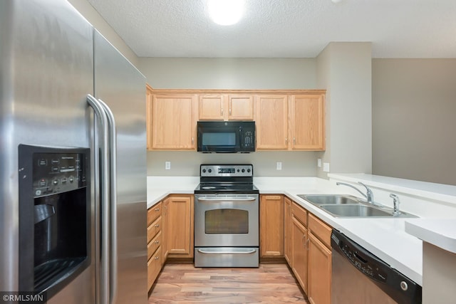 kitchen with a textured ceiling, light wood-style flooring, a sink, light countertops, and appliances with stainless steel finishes